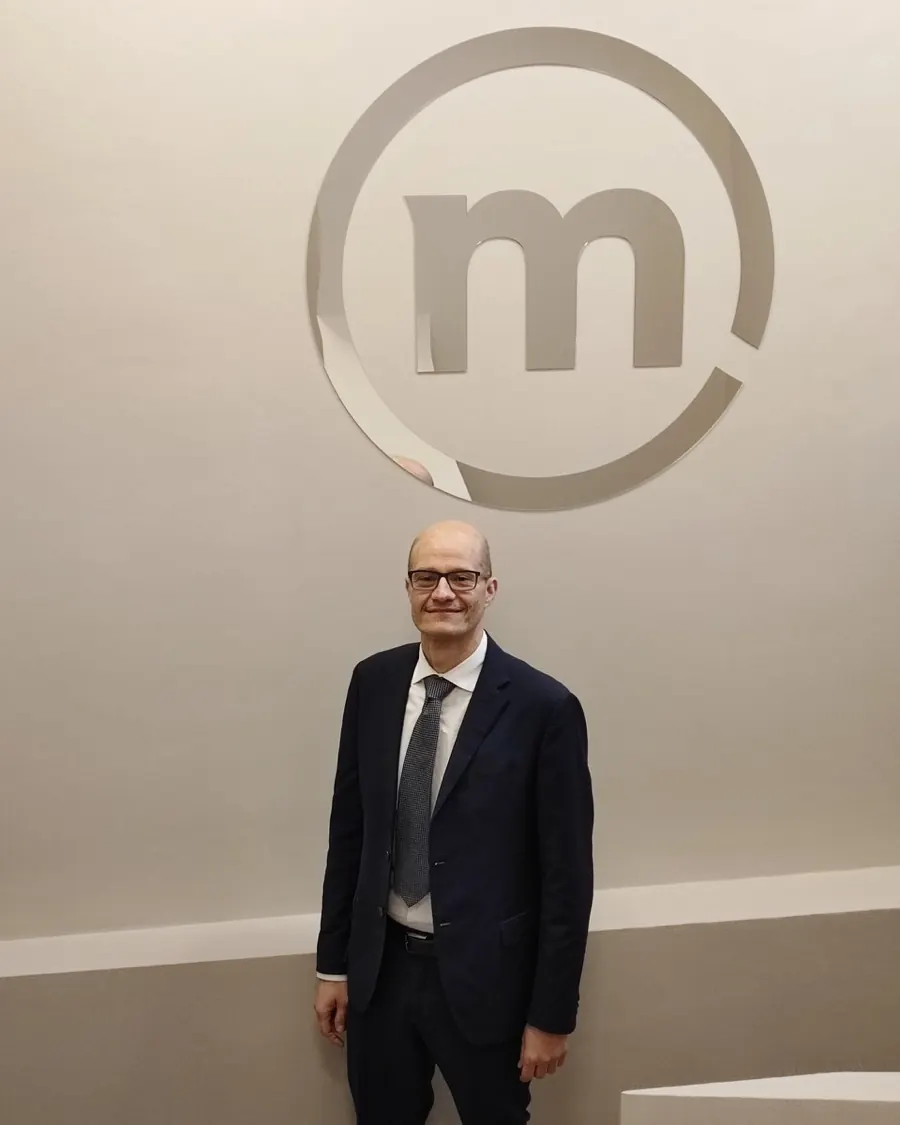 Simoneluca Mazzolini sorridente davanti al logo Banca Mediolanum